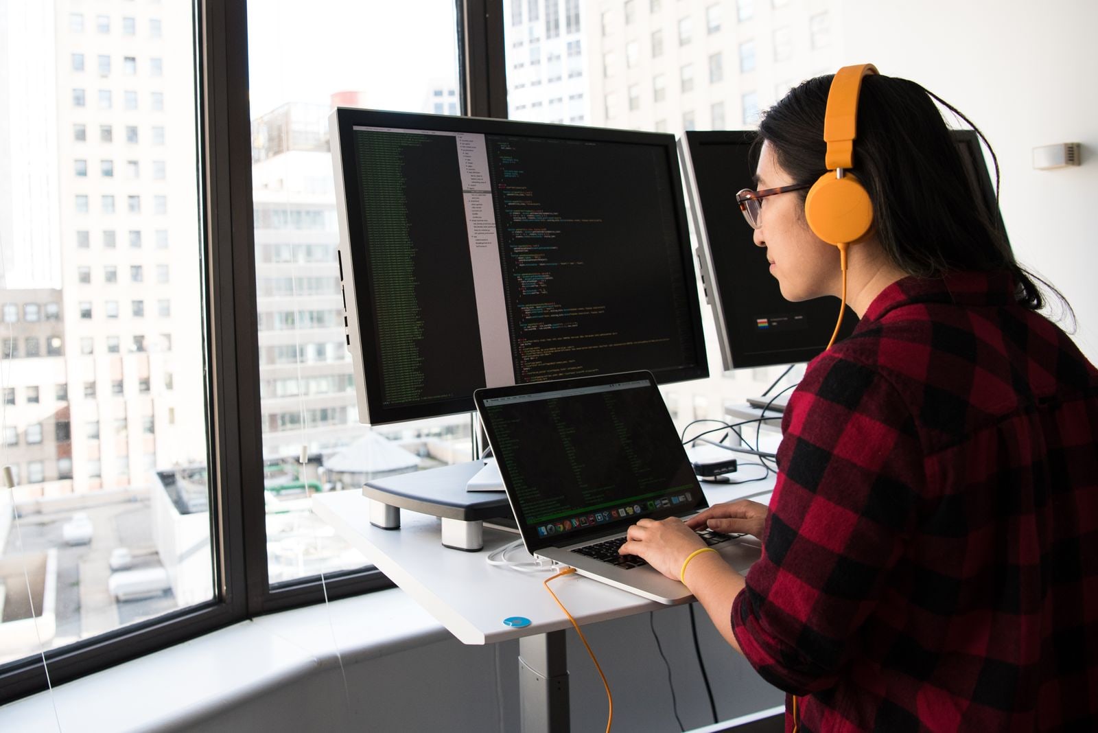 Profesional trabajando con una computadora portátil y monitores de código