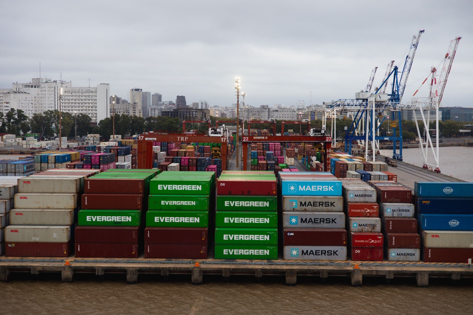 Terminal portuaria con contenedores, grúas y edificios al fondo